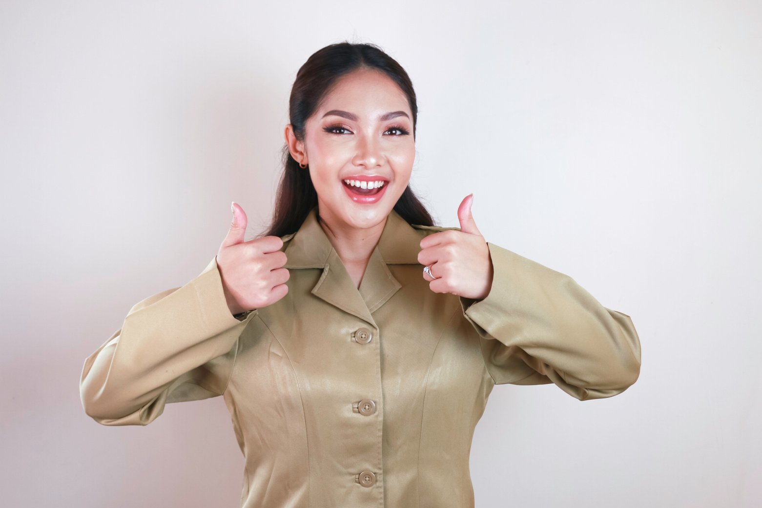 A Young Asian Woman in Brown Khaki Uniform Showing Thumbs up or OK Sign. Indonesian Government Worker.